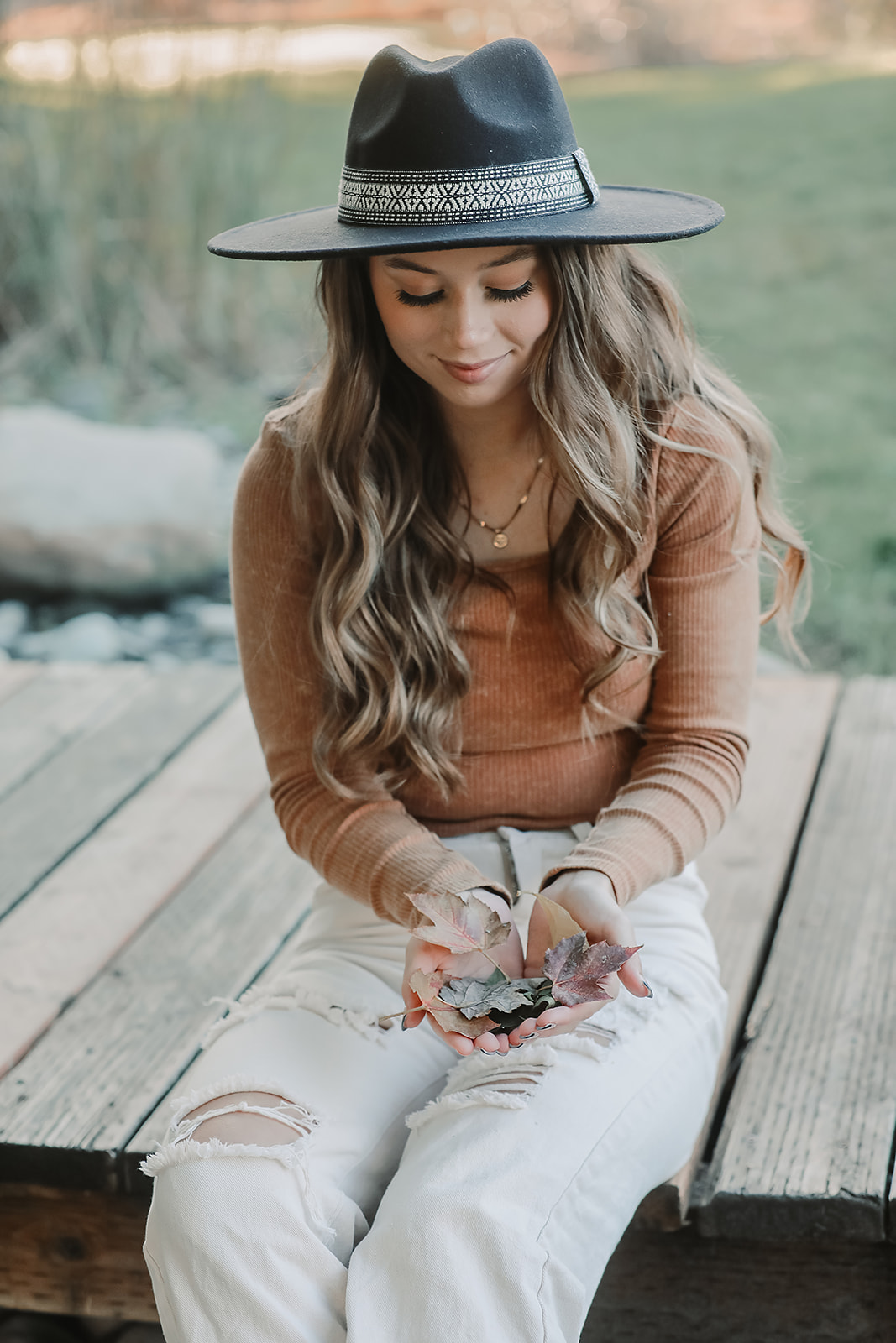 Senior holding fallen autumn leaves on a wooden bridge