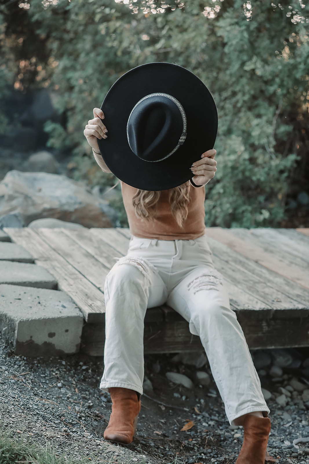 Playful portrait hiding behind a black wide-brim hat